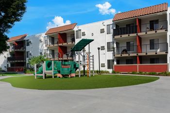 a playground in the middle of an apartment building with a large green swing set